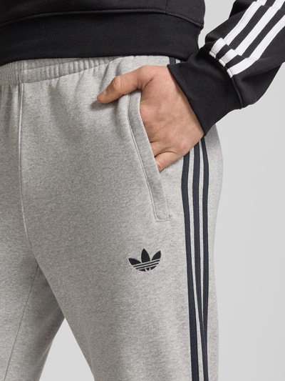 Männermodel trägt Sweatpants mit elastischem Bund von adidas Originals aus Katoenmix, los model, labelstitching, steekzakken, detailaufnahme.