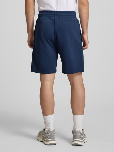 Männermodel trägt Shorts mit Logo von The North Face in Dunkelblau, Baumwoll-Mix, Regular-Fit, elastischer Bund, Ganzkörperansicht Rückansicht.