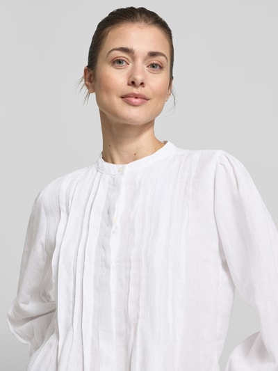 Vrouwenmodel draagt Regular Fit Langarmbluse aus reinem Leinen van Marc O'Polo in effen wit linnen met tuniekkraag, knoopsluiting, plooien en manchetten, flammé textuur, detailopname bovenlichaam.