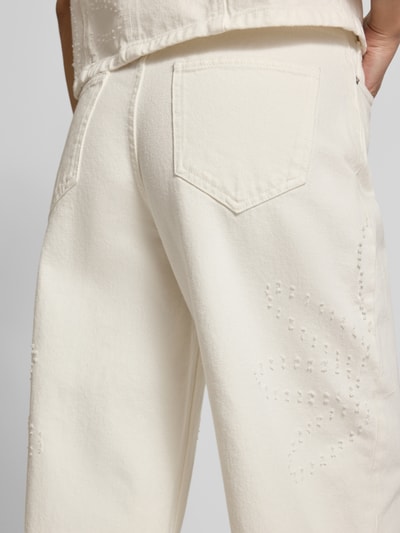 Frauenmodel trägt Wide Fit Jeans in verkürzter Passform Modell 'Dexter' von MSCH Copenhagen aus Reine Baumwolle mit 5-Pocket-Design, Knopf- und Reißverschluss, naturweiße Farbe, strukturierte Baumwoll-Textur, Detailaufnahme Rückansicht.