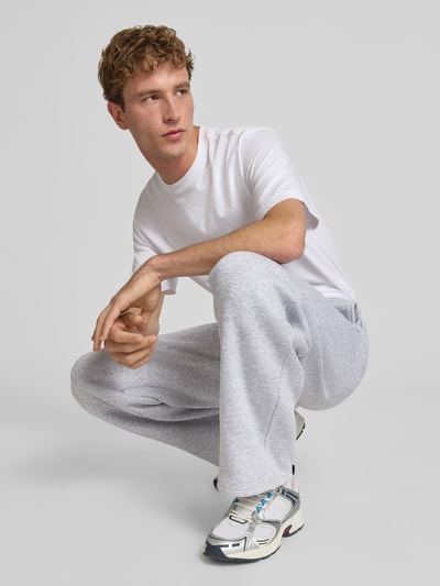 Männermodel trägt Straight Fit Sweatpants mit Logo-Detail von REVIEW in Hellgrau, Baumwoll-Mix, elastischer Bund, Ganzkörperansicht von vorne.