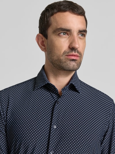 Männermodel trägt Slim Fit Business-Hemd mit Kentkraag van Jake*s, elastische materiaalmix, donkere kleur, patroon, knoopsluiting, Nahaufnahme Oberkörper. Ruglengte maat 39/40: 75 cm, schouderbreedte: 49 cm, mouwlengte: 69 cm.