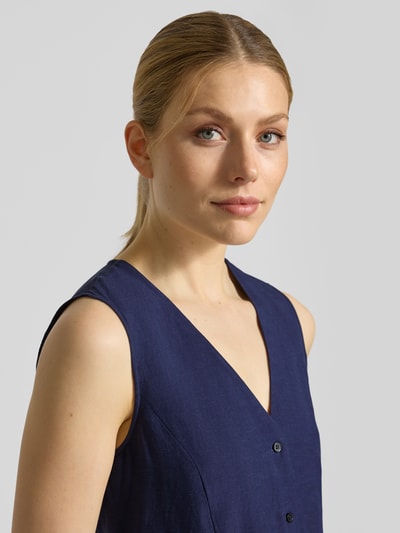 Frauenmodel trägt Weste mit V-Ausschnitt und Schößchen Modell 'ELMO' von EMME in Dunkelblau, glatte Textur, Nahaufnahme Oberkörper. Viskose-Leinen-Mix, Regular Fit, Knopfleiste.