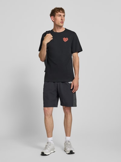 Männermodel trägt T-Shirt mit Label-Print und Rundhalsausschnitt von The North Face, Reine Baumwolle, Regular-Fit, Rückenlänge 74 cm, Ganzkörperansicht von vorne