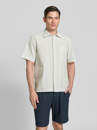 Männermodel trägt Relaxed Fit Freizeithemd aus reiner Baumwolle Modell 'STUART' von SELECTED HOMME, gestreiftes Seersucker-Material, Ganzkörperansicht von vorne.