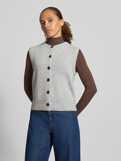 Frauenmodel trägt Regular Fit Strickweste aus Woll-Mix von Christian Berg in Hellgrau mit Knopfleiste und gerippten Abschlüssen, Ganzkörperansicht von vorne.