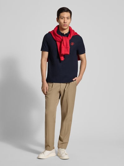 Männermodel trägt Regular Fit Poloshirt aus reiner Baumwolle von Tommy Hilfiger, Optik: Unifarben, Logo-Stitching, Polokragen, Piqué, Ganzkörperansicht von vorne.