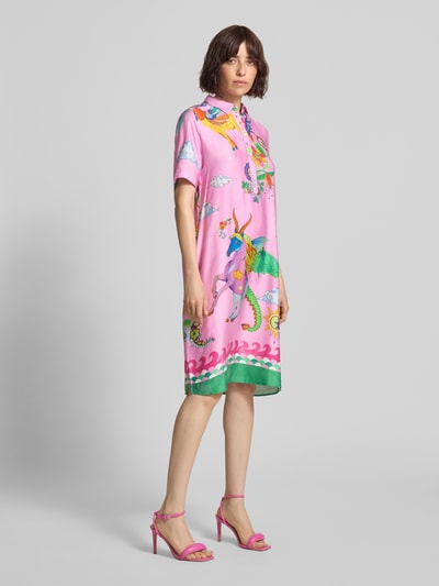 Frauenmodel trägt knielanges Hemdblusenkleid aus Viskose im Allover-Look von Milano Italy, gerade geschnitten, rosa mit bunten Drucken, glatte Textur, farbige Details, Knopfleiste, Ganzkörperansicht von vorne.