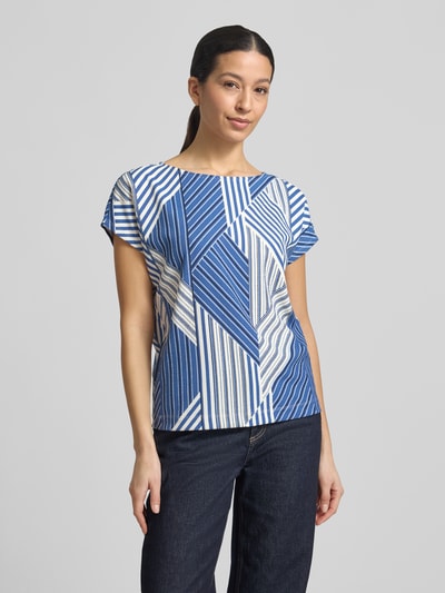Frauenmodel trägt Regular Fit T-Shirt mit Allover-Muster von s.Oliver RED LABEL in Blau und Weiß, U-Boot-Ausschnitt, Musselin-Textur, Ganzkörperansicht von vorne.