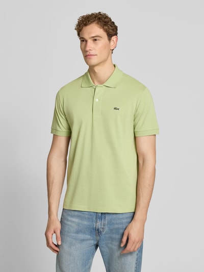 Männermodel trägt Regular Fit Poloshirt aus Baumwoll-Mix von Lacoste in Hellgrün, kurzarm, unifarben, Piqué-Struktur, Ganzkörperansicht von vorne.