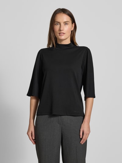 Frauenmodel trägt Longsleeve mit 3/4-Ärmel von Marc Cain aus Baumwoll-Elasthan-Mix, lockerer Schnitt, Stehkragen, schwarze Farbe, Ganzkörperansicht von vorne.