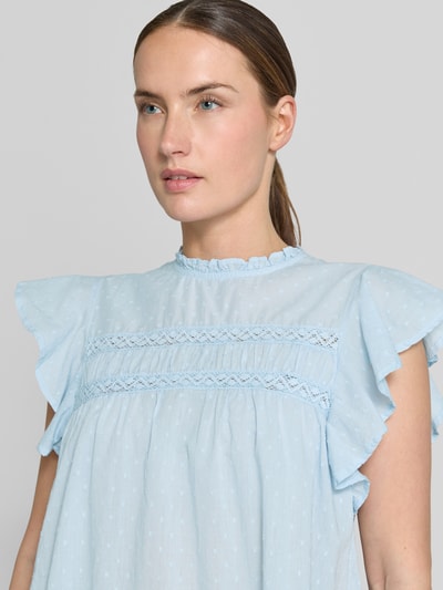 Frauenmodel trägt Regular Fit Blusentop aus reiner bawełna Modell 'TRINE' von Vero Moda, efekt: jednolity kolor, wzór: z kropkami, krój: krój regular fit, kształt kołnierza: kołnierz z falbanami, detale: plisy, marszczenie, pas na plecach, dekolt: okrągły dekolt, zapięcie: guzik, rękaw: krótki rękaw, wykończenie materiału: popelina. Nahaufnahme Oberkörper.