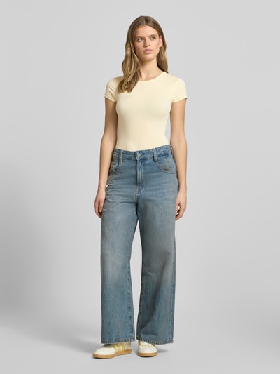 Frauenmodel trägt Slim Fit T-Shirt aus Modal-Mix von Gina Tricot in Hellgelb mit Rundhalsausschnitt und Kurzärmelig, Ganzkörperansicht von vorne, Damen T-Shirt Elastischer-Modal-Mix Rückenlänge 54 cm Größe S.
