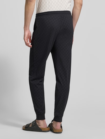 Männermodel trägt Sweatpants mit Logo-Muster und elastischem Bund von JOOP! Collection, reine Baumwolle, Regular Fit, Ganzkörperansicht Rückansicht