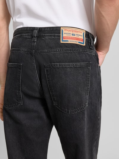 Männermodel trägt Loose Fit Jeans mit Lyocell-Anteil von Diesel, schwarze Baumwoll-Lyocell-Mix, Label-Detail, Nahaufnahme Rückansicht.