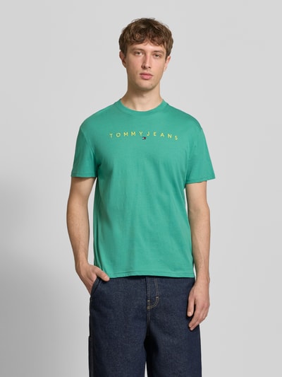 Männermodel trägt Regular Fit T-Shirt aus reiner Baumwolle von Tommy Jeans, Optik: Unifarben, Rundhals, Kurzarm, Label-Stitching-Applikation, Ganzkörperansicht von vorne.