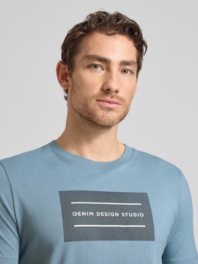 Männermodel trägt Regular Fit T-Shirt aus reiner Baumwolle von Tom Tailor Denim in Optik: Unifarben mit Label-Schriftzug, Nahaufnahme Oberkörper.
