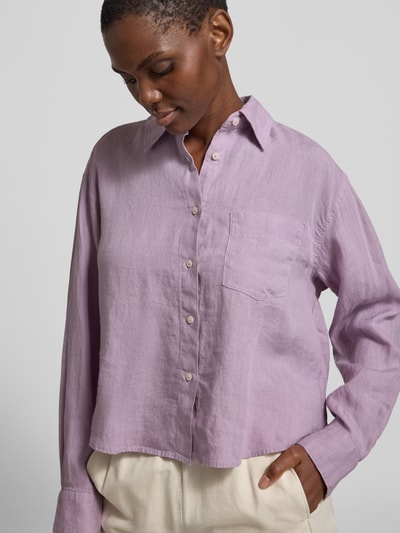 Frauenmodel trägt Relaxed Fit Hemdbluse aus reinem Leinen von Marc O'Polo in Optik: Unifarben, flieder, Nahaufnahme Oberkörper. Passform: Relaxed-Fit, Kragenform: Hemdblusenkragen, Ausschnitt: V-Ausschnitt, Verschluss: einreihige Knopfleiste, Ärmelform: Langarm, Ärmelabschluss: Manschette, Rumpfabschluss: Abgerundet, Taschen: Brusttasche, Material: Leinen.