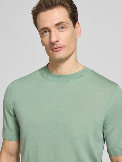 Männermodel trägt Regular Fit Strick-Shirt aus reiner Schurwolle Modell 'H-UMAURO' von BOSS in Mintgrün, Nahaufnahme Oberkörper. Unifarbener Look, Rundhals, Kurzarm, gerippte Abschlüsse, feine Stricktextur.