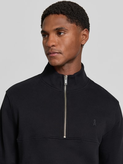 Männermodel trägt Regular Fit Troyer aus reiner Baumwolle Modell 'WAARLO' von ARMEDANGELS in Schwarz mit silbernem Zipper, Nahaufnahme Oberkörper, Herren Troyer von ARMEDANGELS.