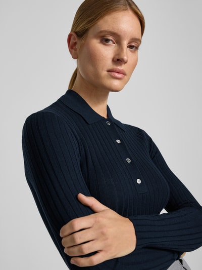 Vrouwenmodel draagt Henley-Shirt uit wol van Style Icon Collection, donkerblauw riblook, puur katoen, skinny fit, polokraag, tricotlook, met lange mouwen, ruglengte maat S 59 cm, mouwlengte maat S 66 cm, Nahaufnahme Oberkörper.