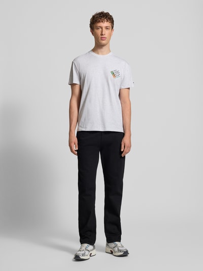 Männermodel trägt Straight Fit Jeans aus Baumwoll-Mix Modell 'RYAN' von Tommy Jeans in dunkler Denim-Optik, 5-Pocket-Design, Ganzkörperansicht von vorne.
