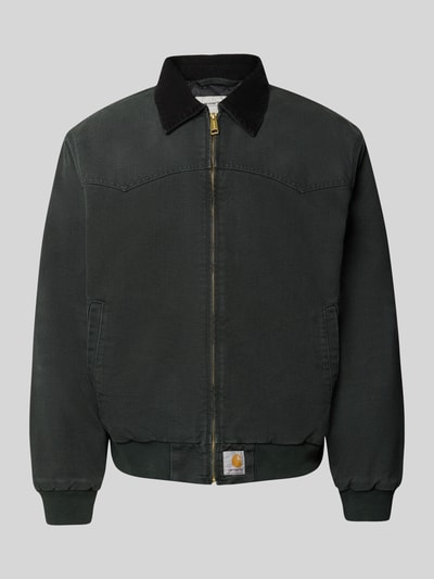 Produktfoto, Jacke mit Reißverschluss und Label-Detail Modell 'Santa Fe' von Carhartt Work In Progress aus reiner Baumwolle in Dunkelgrün, sichtbare Struktur, goldfarbener Reißverschluss, Umlegekragen, Regular Fit, neutrale graue Hintergrundfarbe.