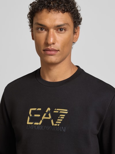Männermodel trägt Sweatshirt mit Logo und Rundhalsausschnitt von EA7 Armani aus reiner Baumwolle, Regular-Fit, Nahaufnahme Oberkörper.