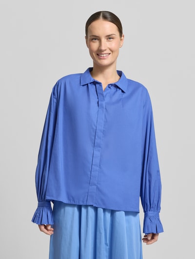 Vrouwenmodel draagt blouse met verdekte knoopsluiting van Milano Italy, puur katoen, recht model, kentkraag, ruches aan mouwen, ruglengte 60 cm, mouwlengte 64 cm, blauw, gladde textuur, voorkantaanzicht bovenlichaam.
