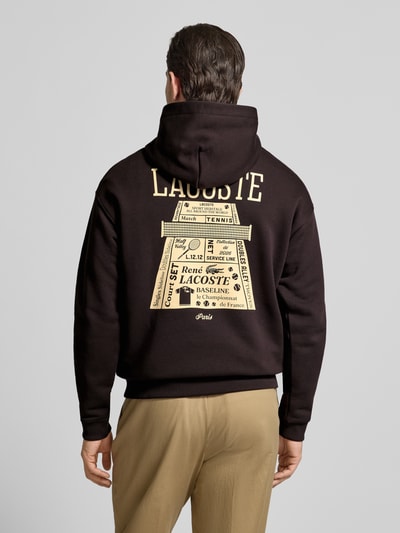 Männermodel trägt Regular Fit Hoodie aus reiner Baumwolle von Lacoste, Optik: Unifarben, Motiv-Print, Sweat, Ganzkörperansicht Rückansicht.