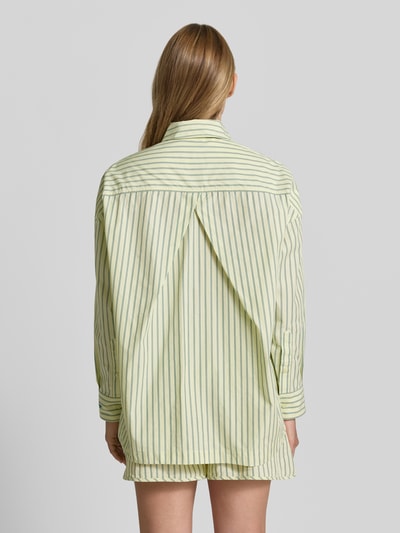 Modelka kobieca ma na sobie Oversized Hemdbluse aus reiner Baumwolle Modell 'BOSTATTA' od BOSS Orange, pastelowe, zielono-białe paski, luźny krój, detal z kontrafałdą z tyłu, czysta bawełna, widok całej sylwetki z tyłu.