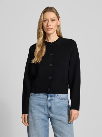 Frauenmodel trägt Cardigan aus Viskose-Mix mit Umlegekragen Modell 'Turea' von Someday, schwarze Farbe, glatte Textur, Knopfleiste, gerader Schnitt, Ganzkörperansicht von vorne.