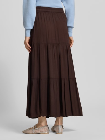 Frauenmodel trägt ausgestellten Maxi-Rock aus reiner Viskose Modell 'MIKKA' von Only in Dunkelbraun mit Volants und Crinkle-Struktur, Ganzkörperansicht Rückansicht.