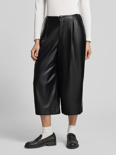 Frauenmodel trägt Straight Fit Hose in Midilänge mit Bundfalten von Oui in schwarzer Leder-Optik, fließende Struktur, Nahaufnahme Oberkörper. Damen Hose von Oui, Leder-Optik, Midilänge, Bundfalten, Haken- und Reißverschluss, Bundweite Größe 36: 39 cm, Innenbeinlänge: 50 cm.