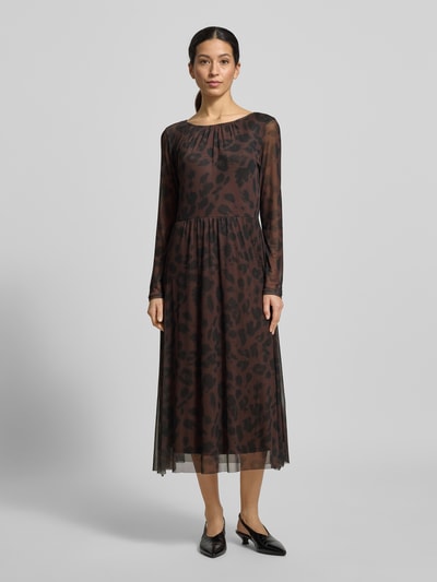 Kobiece modelka nosi Tailliertes Freizeitkleid mit Allover-Muster od Tom Tailor, efekt: wzór na całej powierzchni, taliowany krój, długość midi, okrągły dekolt, zapięcie na guzik i oczko, długi rękaw, prosty dół, wykończenie: szyfon, widok całej sylwetki z przodu.