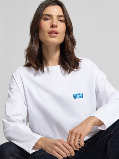Vrouwenmodel draagt Longsleeve mit Label-Print Modell 'GIXY' van American Vintage in wit katoen, relaxed fit, ronde hals, Nahaufnahme bovenlichaam.