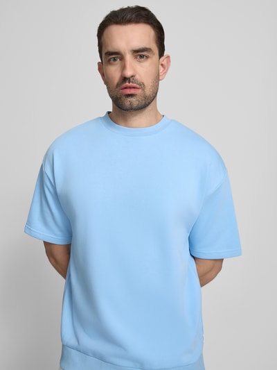 Männermodel trägt Oversized T-Shirt mit Rundhalsausschnitt von Lindbergh, Baumwoll-Mix, Label-Detail, hellblau, Nahaufnahme Oberkörper