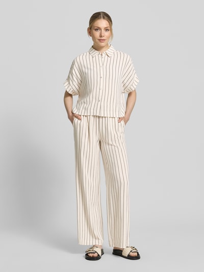 Modelka nosi Loose Fit Weite Hose aus Viskose-Leinen-Mix Modell 'VIVA-GULIA' od Selected Femme, kremowe pionowe paski, wysoki stan, elastyczny pas z tunelem, kieszenie z przodu, materiał to mieszanka wiskozy i lnu, optyka w całości wzorzysta, krój loose fit, zdjęcie całopostaciowe z przodu.