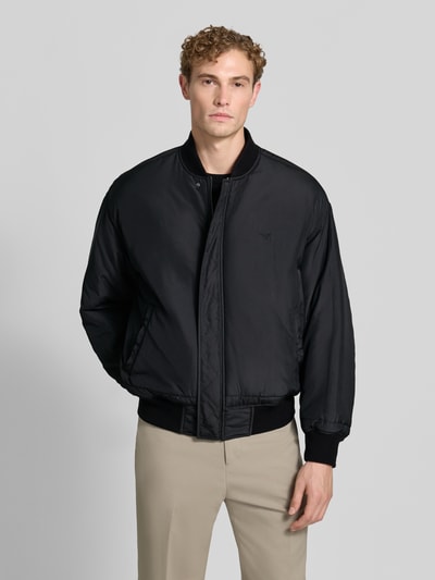Männermodel trägt Bomberjacke mit Stretch-Anteil von Emporio Armani in Schwarz, satinierte Optik, lockere Passform, Ganzkörperansicht von vorne.