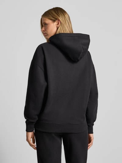 Frauenmodel trägt Relaxed Fit Hoodie aus Baumwoll-Mix Modell 'Clarita' von PEGADOR, Schwarz, gerippte Abschlüsse, Rückansicht, Ganzkörperansicht Rückansicht.
