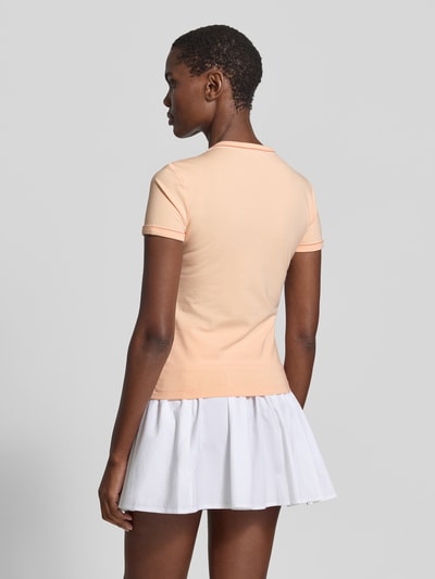 Frauenmodel trägt Slim Fit T-Shirt aus Baumwoll-Mix von Lacoste in Apricot, unifarben, mit Logo-Stitching und Kontrastpaspel, Rückansicht Ganzkörperansicht.