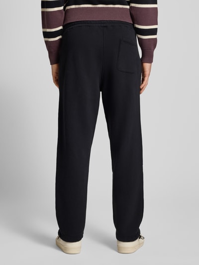 Männermodel trägt schwarze Sweatpants mit elastischem Bund Modell 'Script' von BLKVIS aus reiner Baumwolle im Relaxed-Fit, Ganzkörperansicht Rückansicht.