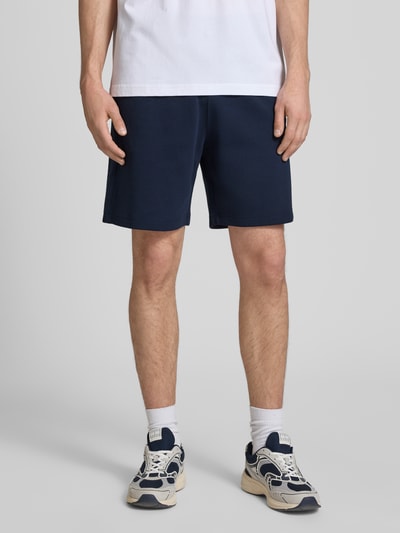 Männermodel trägt Shorts mit Label-Stitching mit elastischem Bund von CHAMPION in Dunkelblau, Baumwoll-Mix, Regular Fit, Ganzkörperansicht von vorne.