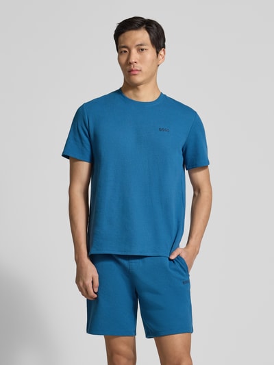 Männermodel trägt Regular Fit Pyjama-Oberteil aus Baumwoll-Mix Modell 'WAFFLE' von BOSS, unifarbenes Blau, Piqué-Textur, Nahaufnahme Oberkörper.