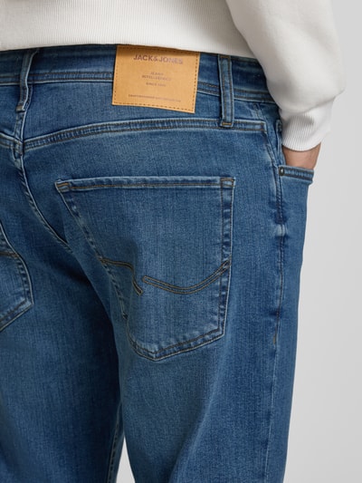 Männermodel draagt Straight Fit Jeans in 5-pocketmodel model 'Mike' van JACK & JONES, katoenmix, blauwe denim, detailopname achterzijde. Bandwijdte maat 32/32: 43 cm, binnenbeenlengte: 77 cm, knoop- en ritssluiting.