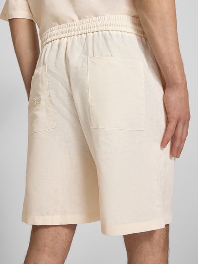 Männermodel trägt Leinenshorts mit elastischem Bund und Tunnelzug von ANOTHER COTTON LAB, cremefarben, Regular-Fit, Detailaufnahme Rückansicht. Herren Shorts aus reinem Leinen, Bundweite in Größe M 42 cm, Innenbeinlänge 20 cm, glatte Textur.
