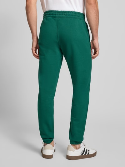 Männermodel trägt Sweatpants mit elastischem Bund von adidas Originals in Grün, Baumwoll-Mix, lockerer Schnitt, Ganzkörperansicht Rückansicht.