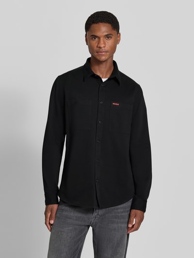 Männermodel trägt Straight Fit Hemdjacke aus Baumwolle Modell 'Egrin' von HUGO in Schwarz, glatte Struktur, Herren Hemdjacke, Ganzkörperansicht von vorne.