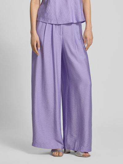 Frauenmodel trägt Wide Fit Stoffhose aus Viskose-Mix Modell 'Finja' von GUIDO MARIA KRETSCHMER WOMAN in Flieder, Bundfalten, Haken- und Reißverschluss, zarte strukturierte Oberfläche, Ganzkörperansicht von vorne.