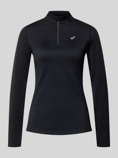 Frauenmodel trägt Funktionsshirt mit Stehkragen und Reißverschluss von ASICS, schwarz, Slim Fit, Longsleeve, Logo, Ganzkörperansicht von vorne. Material-Mix mit Stretch-Anteil, Rückenlänge bei Größe S 56 cm.